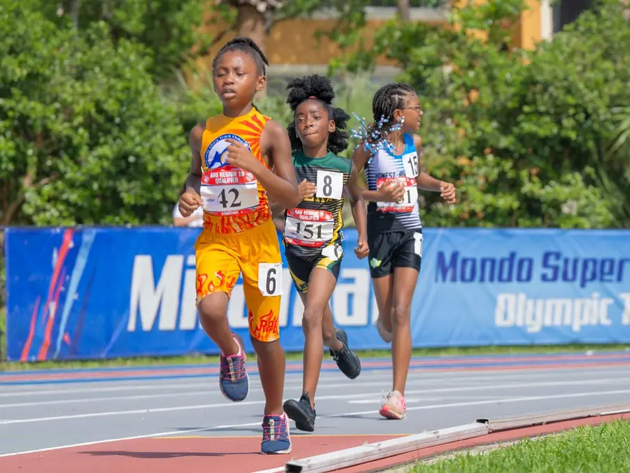 Sprinters racing past a Mondo track banner