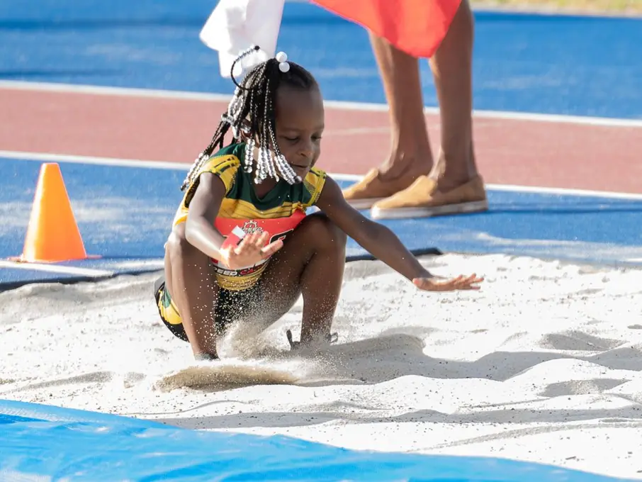 Young long jumper landing in the sand