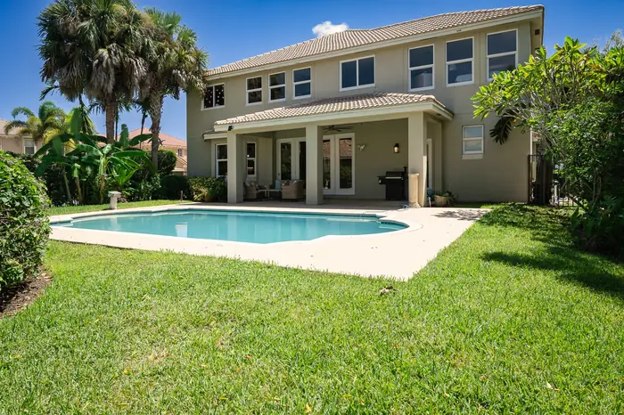 Backyard pool and covered patio behind a two-story home