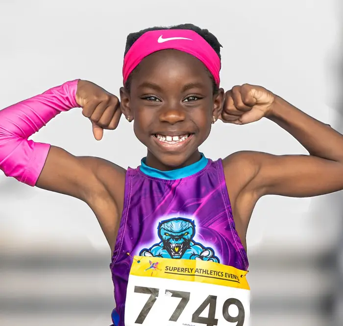 Smiling Superfly athlete in a pink headband flexing