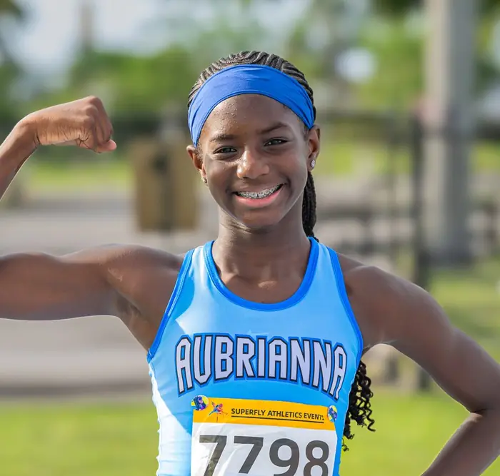 Athlete in a light blue uniform flexing and smiling